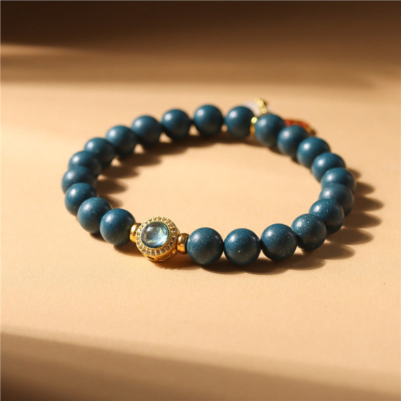 Blue beaded bracelet with a gold clasp on a beige background