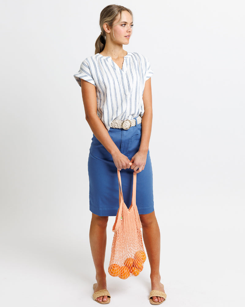 Woman dress with a skirt and a cotton shirt holding bag of oranges