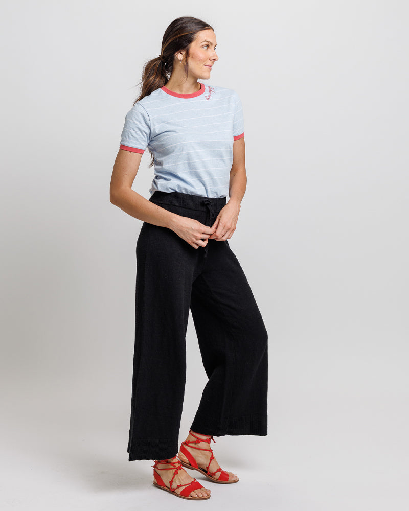 Woman wearing a light gray t-shirt with red trim and black wide-leg pants