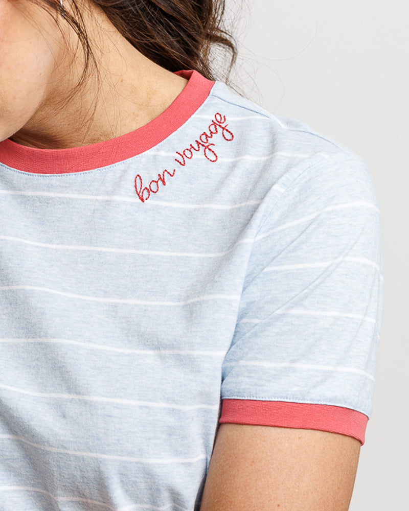 Close-up of a person wearing a striped shirt with 'bon voyage' text.