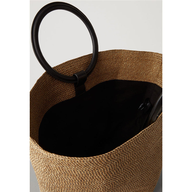 Brown woven bag with a black interior and handle