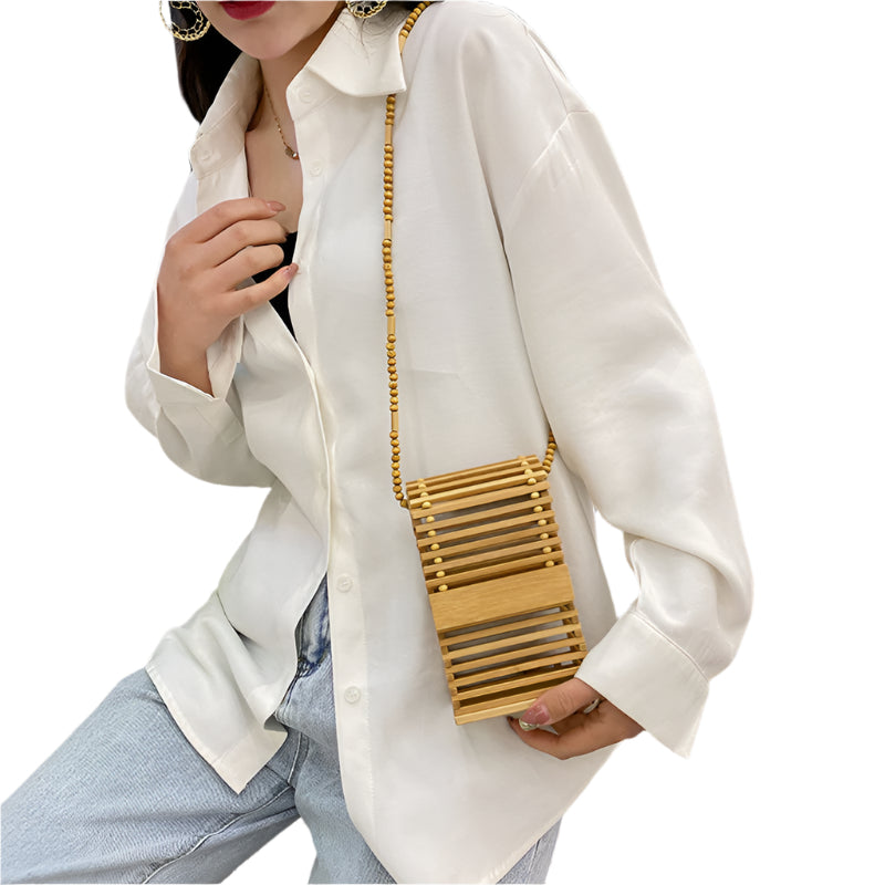 Person wearing a white shirt and holding a brown bamboo bag