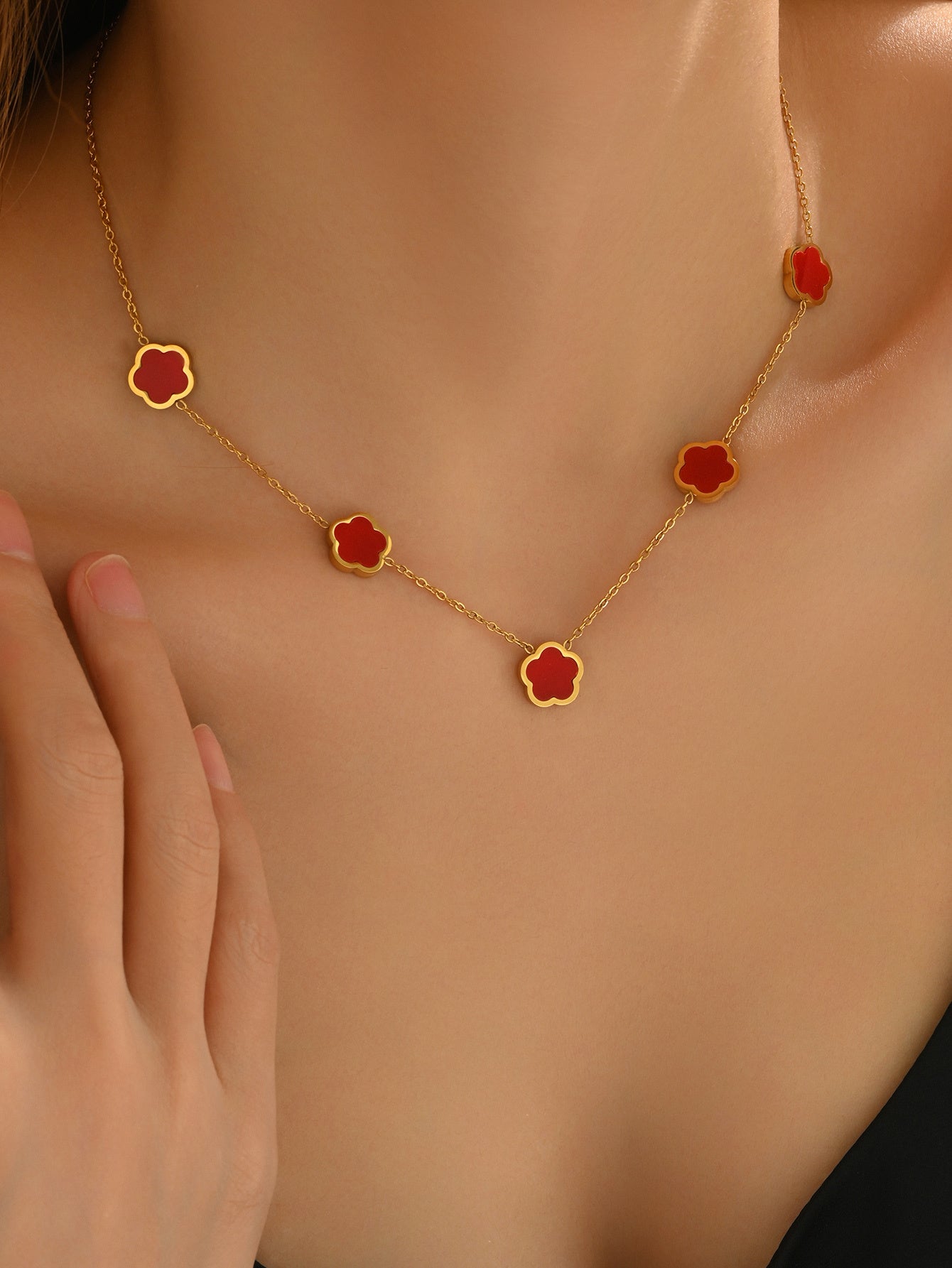 Gold necklace with red flower pendants on a person's neck