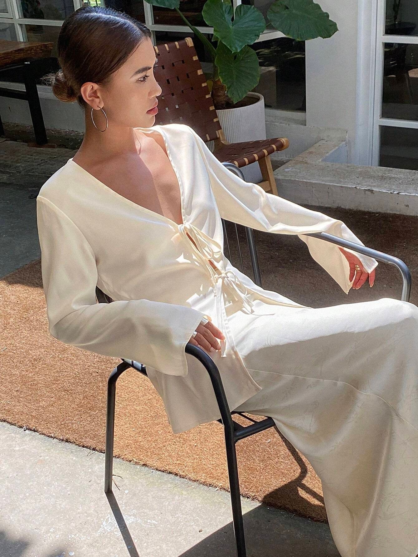 Woman in a white dress sitting outdoors on a chair.