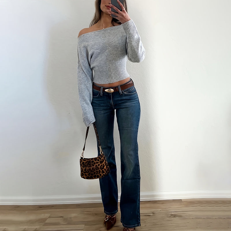 Person wearing a gray off-shoulder cotton sweater and blue jeans, holding a leopard print handbag
