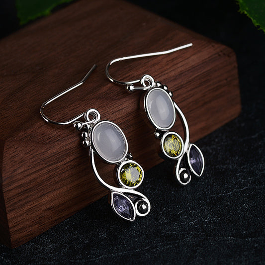 Silver earrings with gemstones on a wooden surface Silver earrings with gemstones on a wooden surface