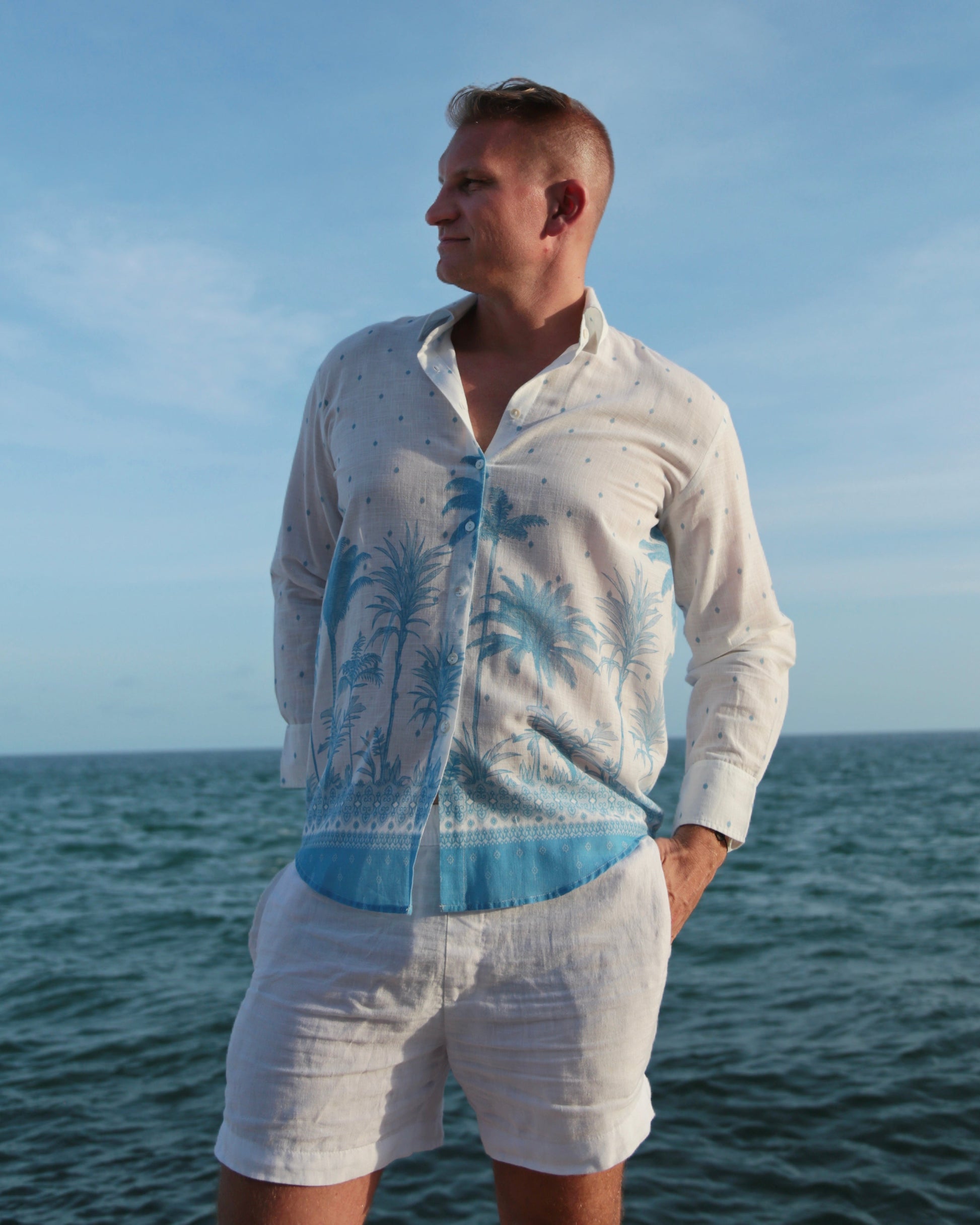 Man wearing a white and blue patterned shirt with a ehite shorts