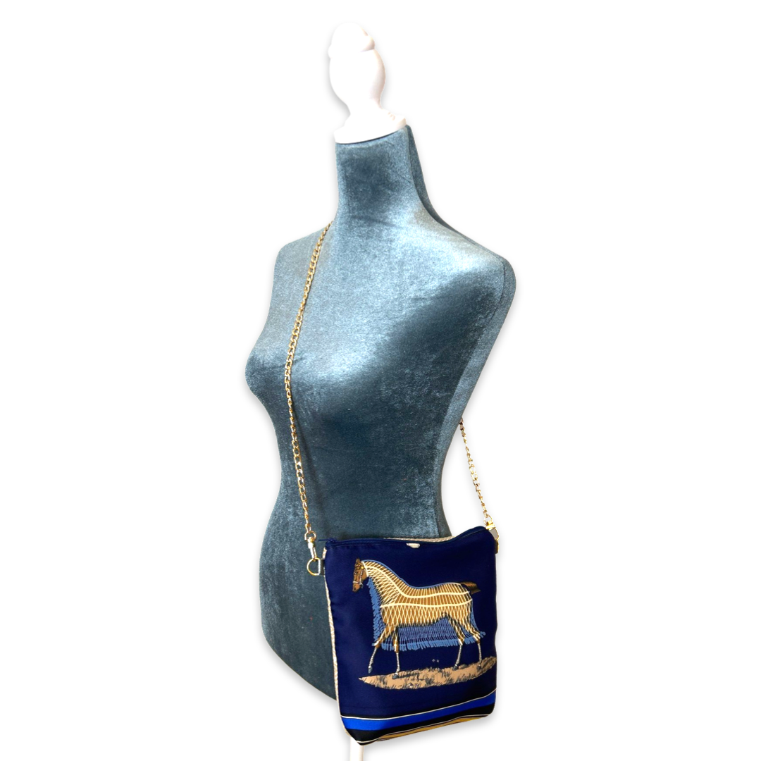 Navy blue handbag with gold horse design on a mannequin against a white background