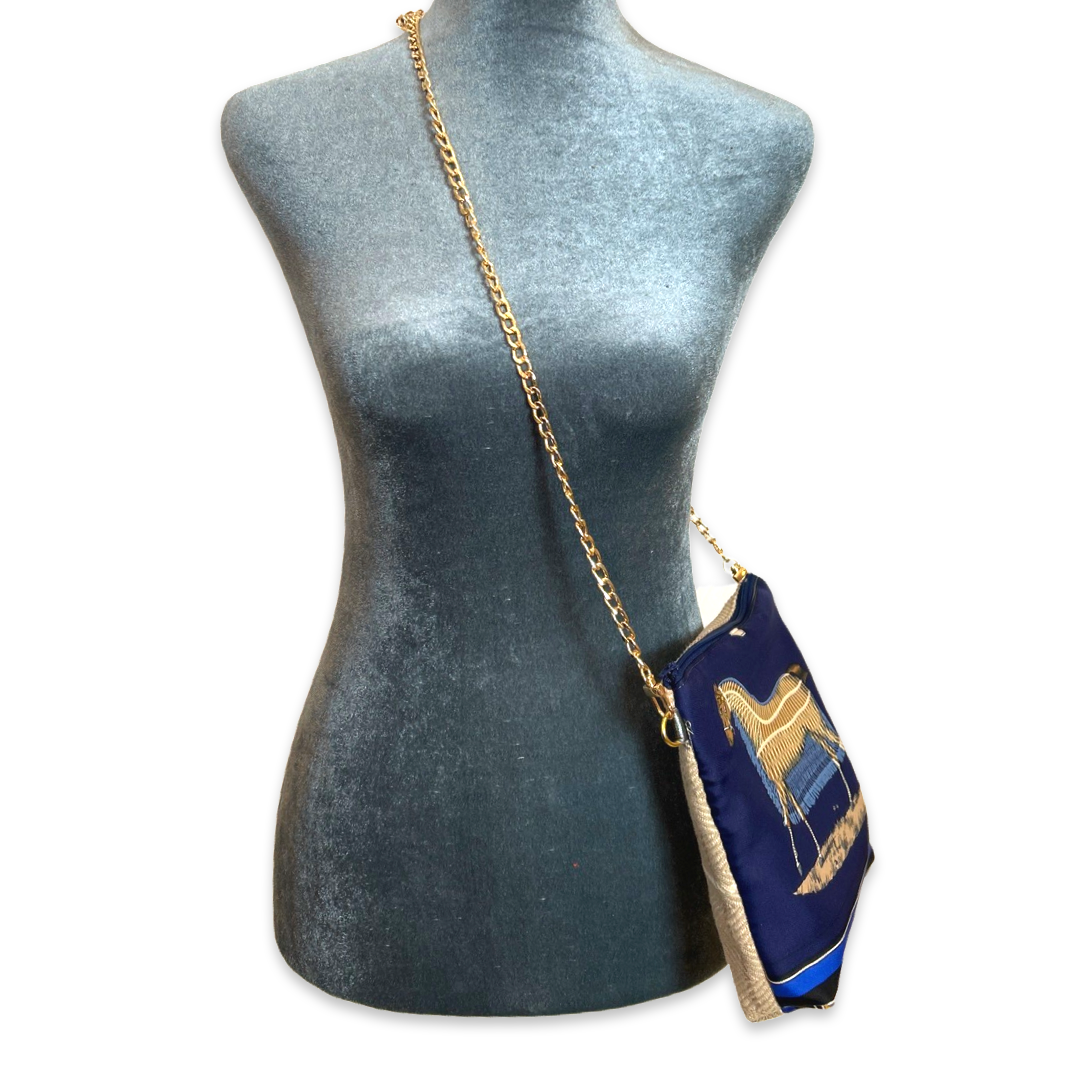 Navy blue handbag with gold chain strap on a mannequin against a white background