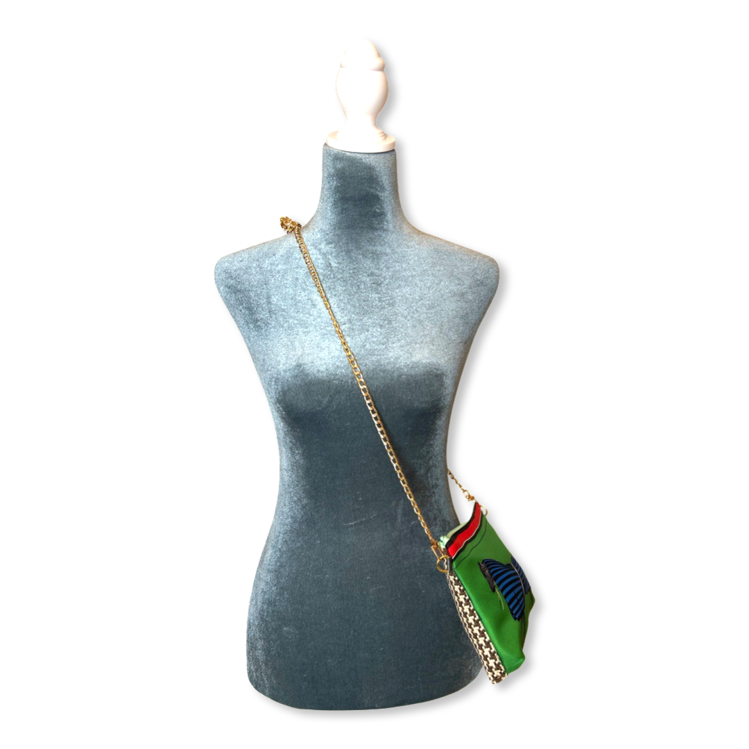 Mannequin wearing a green handbag with a gold chain on a white background