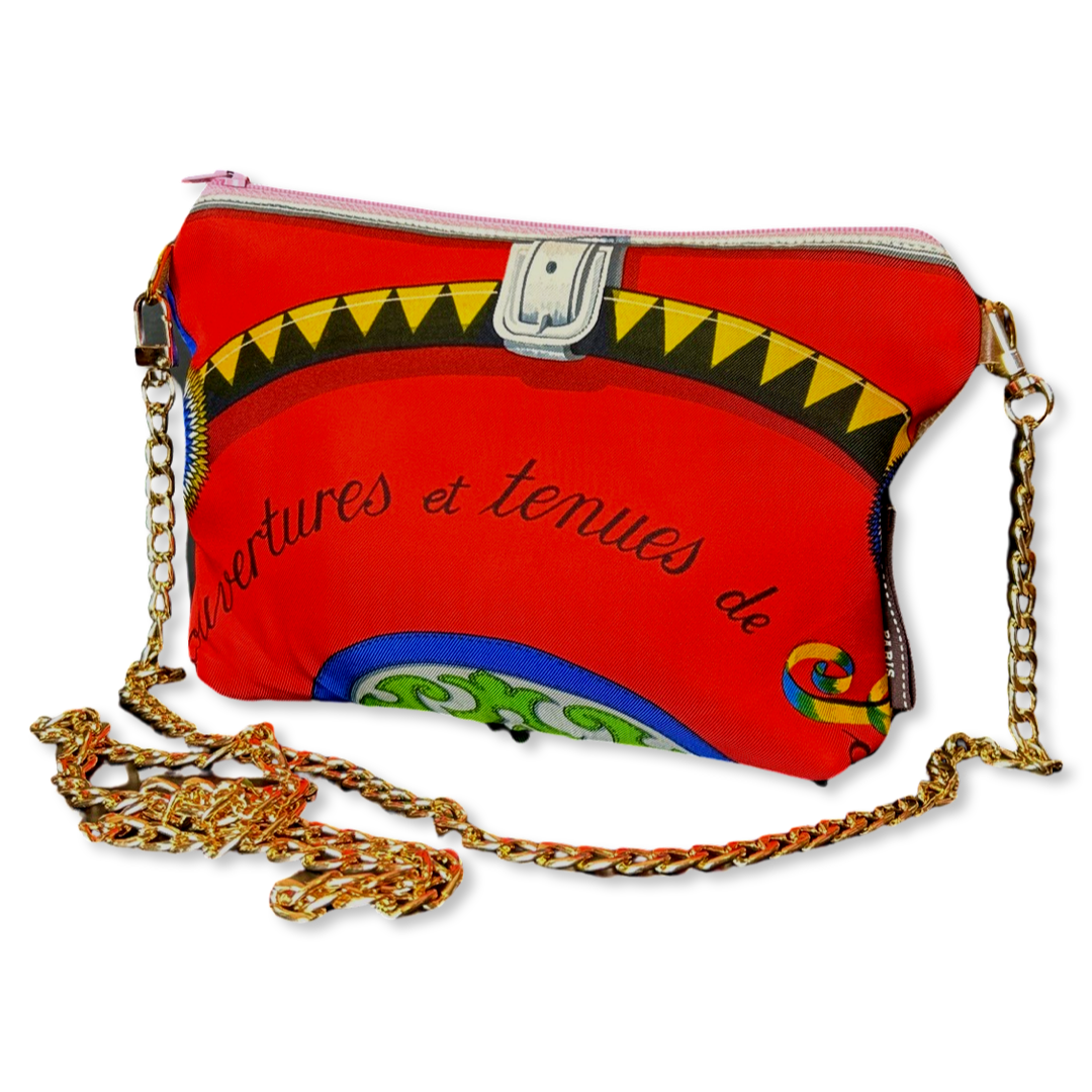 Red handbag with colorful design and gold chain strap on a white background