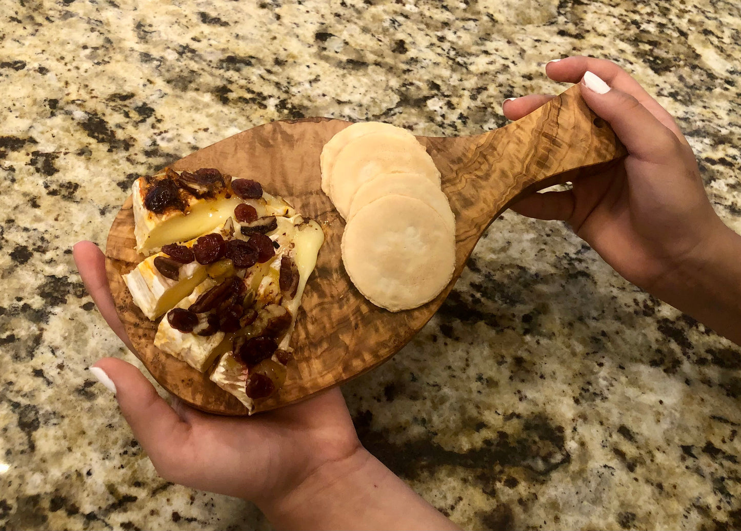 Wooden serving board with brie, dried fruits, and pita bread perfect for parties