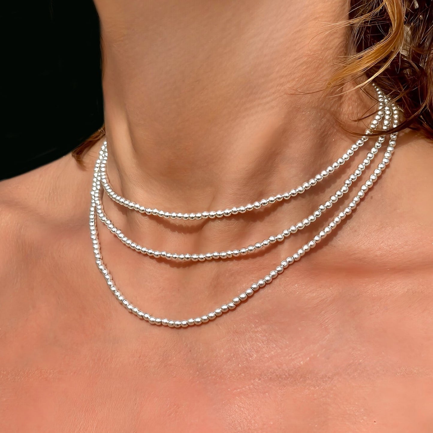 Close-up of a woman wearing a silver necklace with multiple strands.