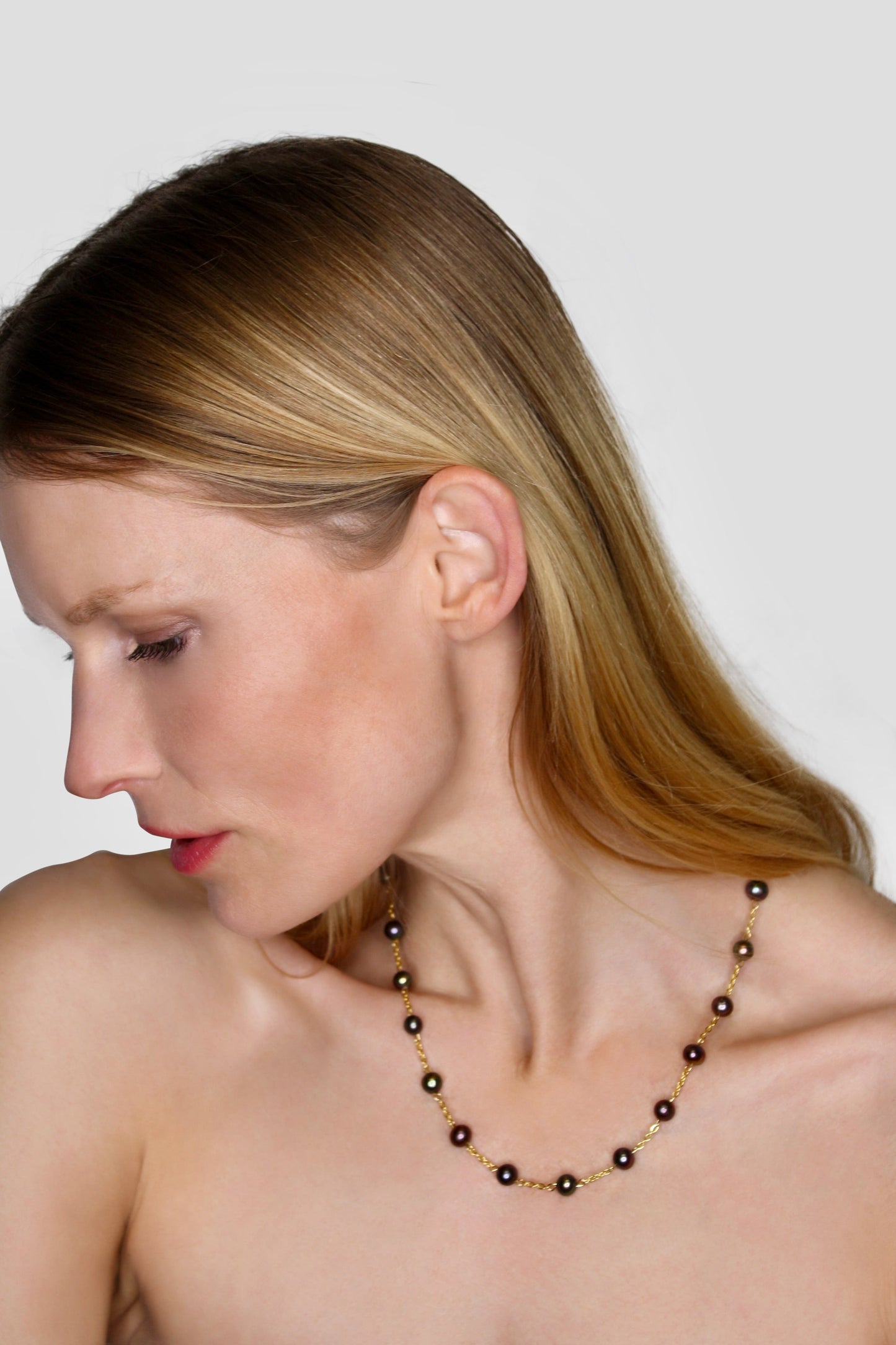 Woman wearing a necklace with a plain background