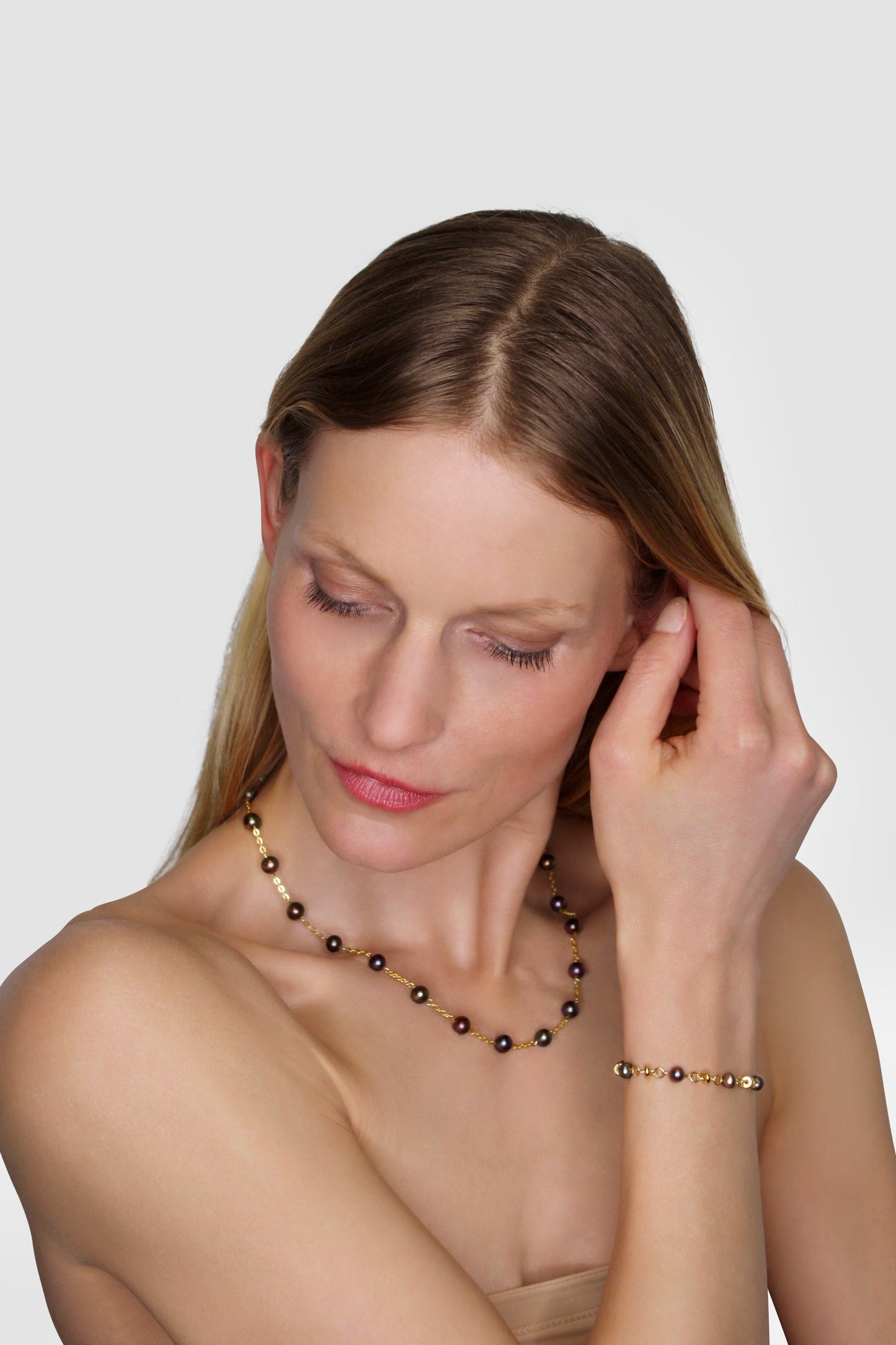 Woman adjusting an earring on a plain background
