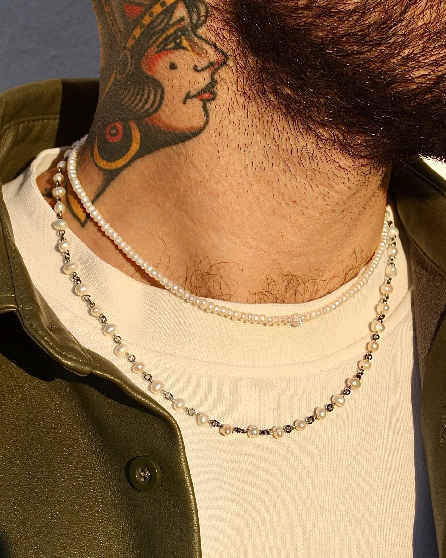 Person wearing a necklace with a tattoo on their neck