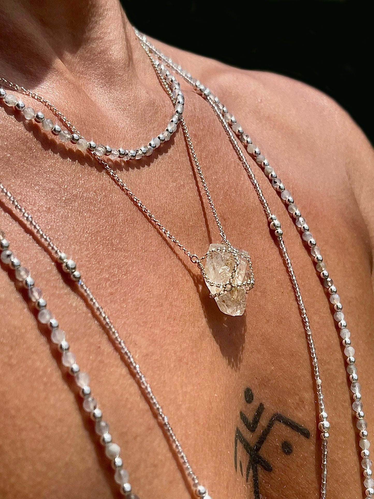 Necklace with a crystal pendant on a person's neck against a dark background