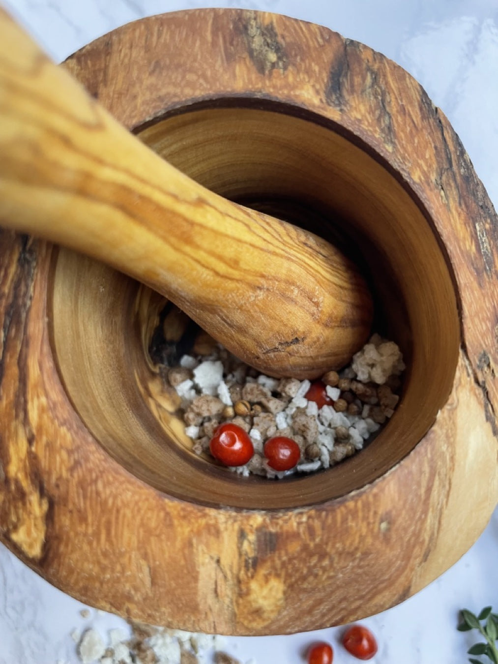 Wooden mortar and pestle with spices and tomatoes