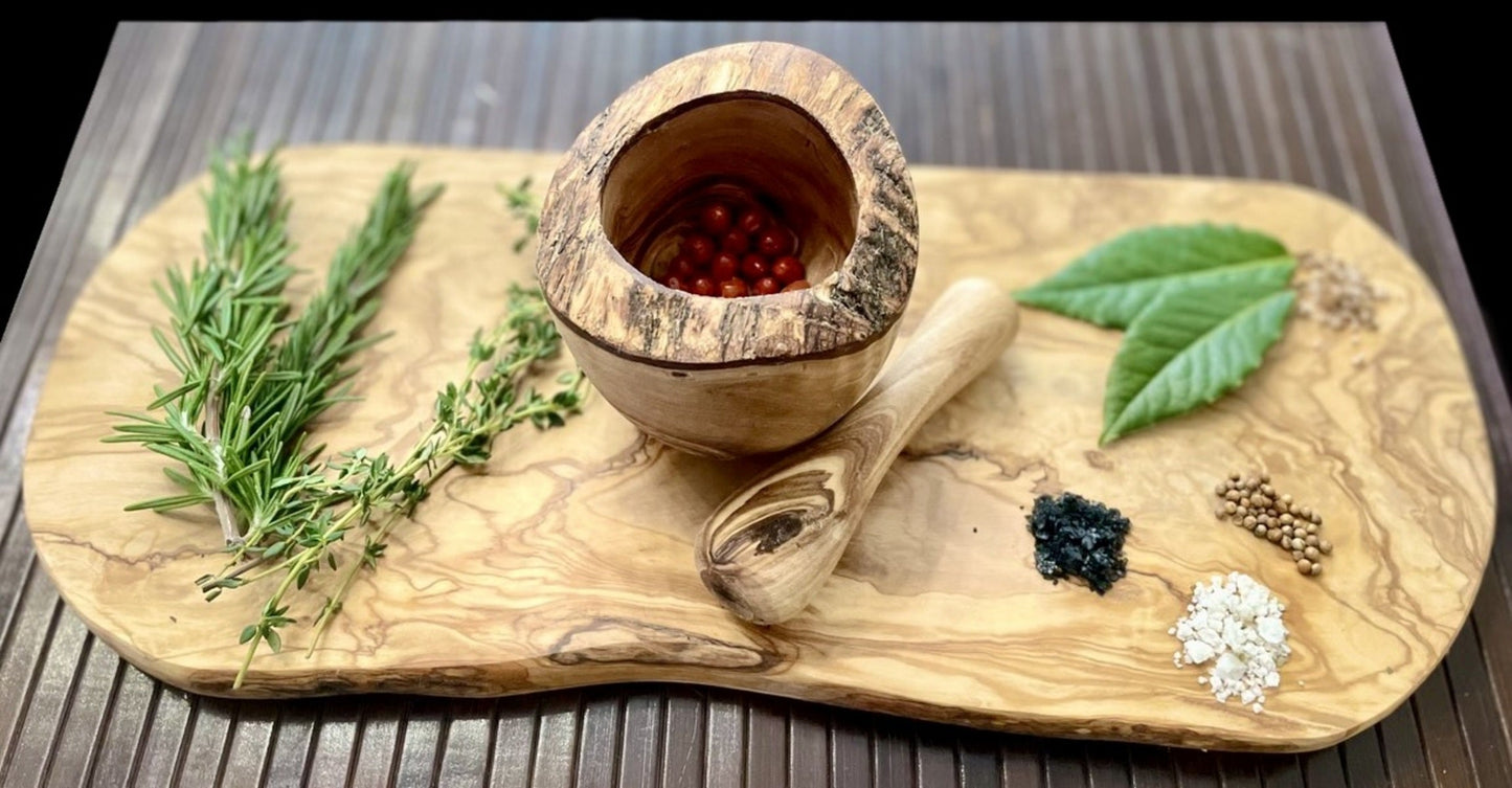 Wooden mortar and pestle with herbs and spices on a wooden board