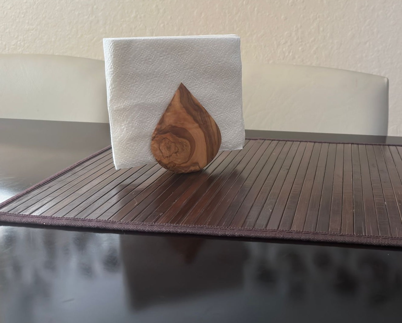 Wooden teardrop-shaped object on a white napkin on a table.