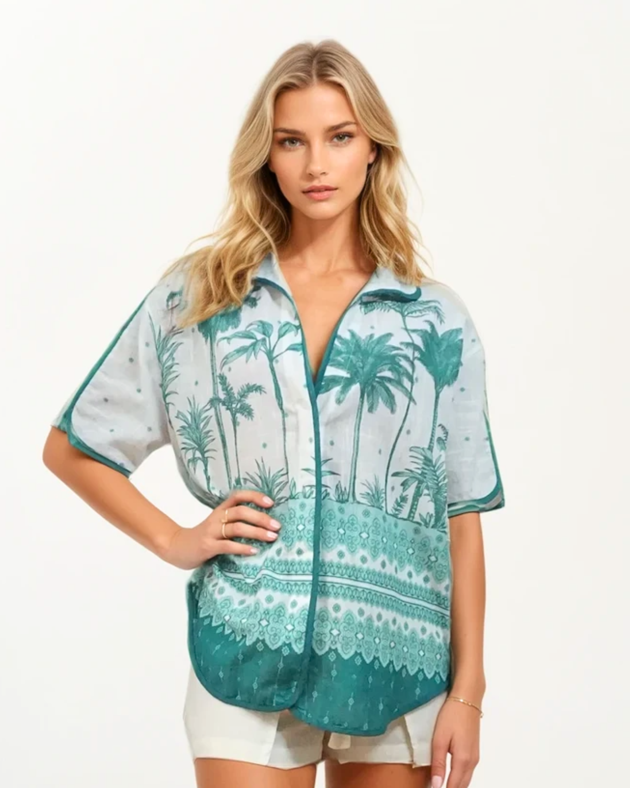 Woman wearing a teal and white patterned shirt with palm tree design on a plain background