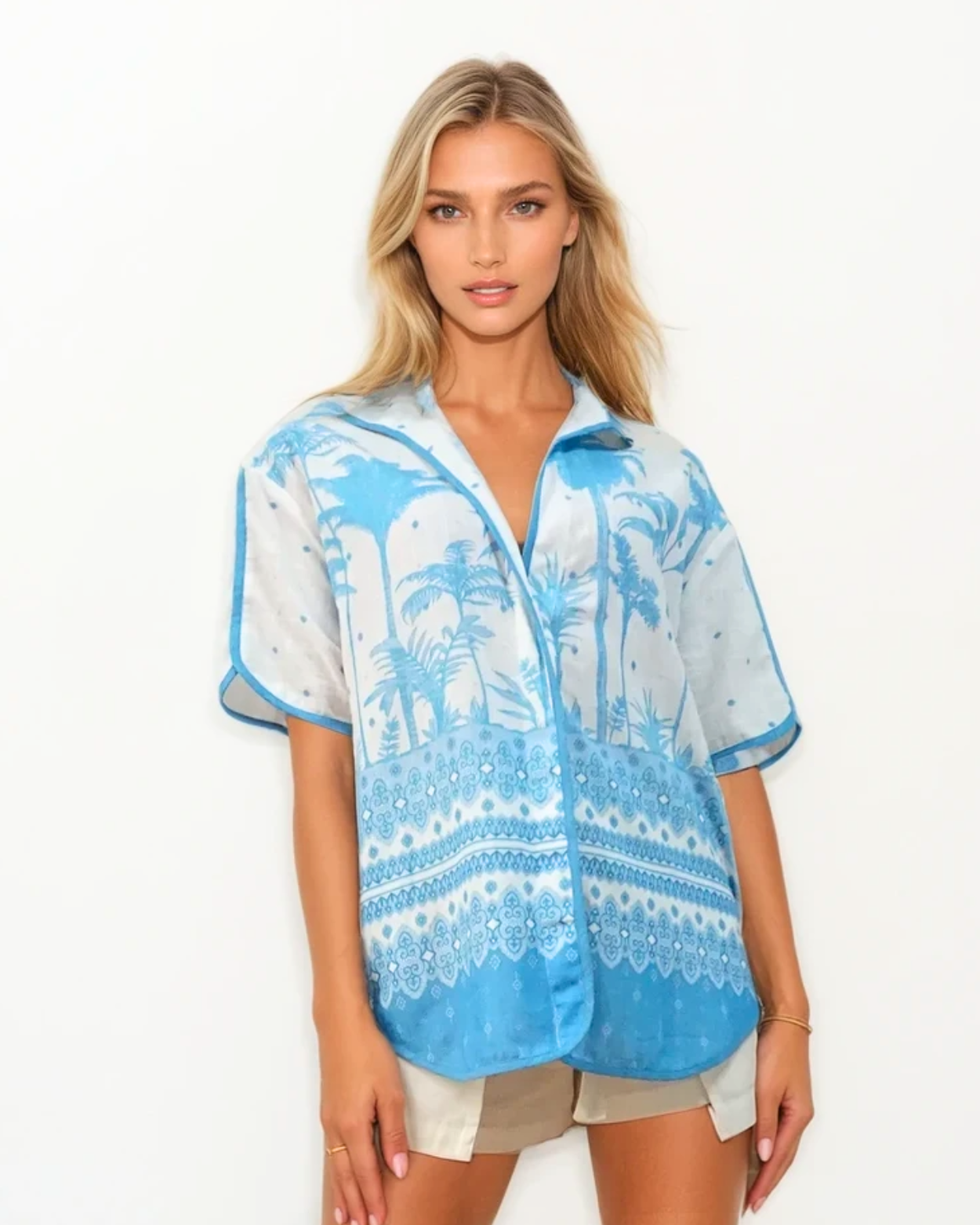 Woman wearing a blue and white patterned shirt with palm tree design on a white background