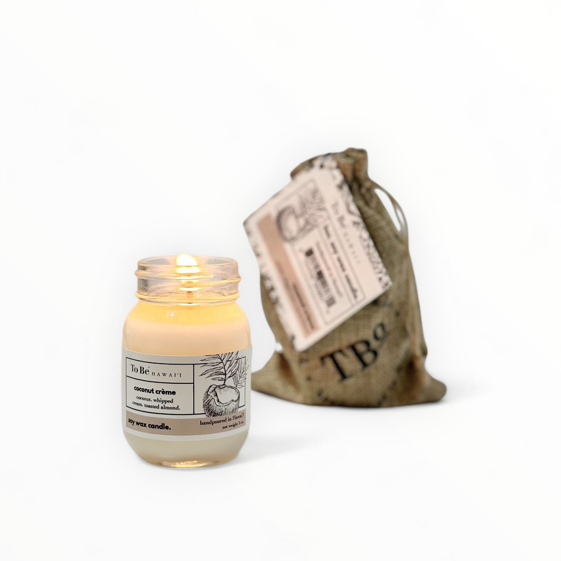 Candle in a glass jar with a label next to a burlap bag