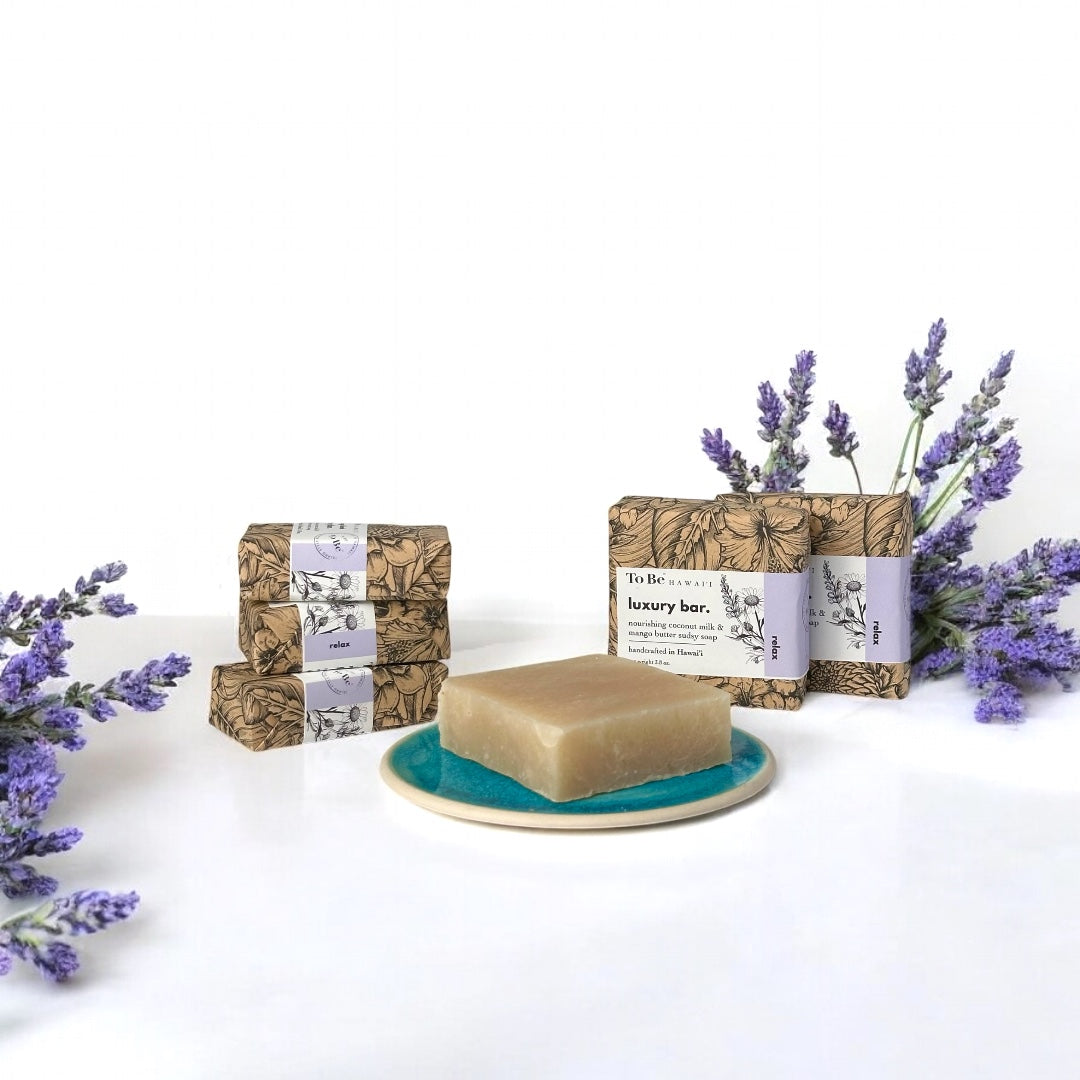 Bar of soap on a teal plate with lavender flowers and wrapped bars of soap