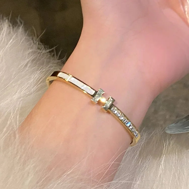 Gold H bracelet on a wrist