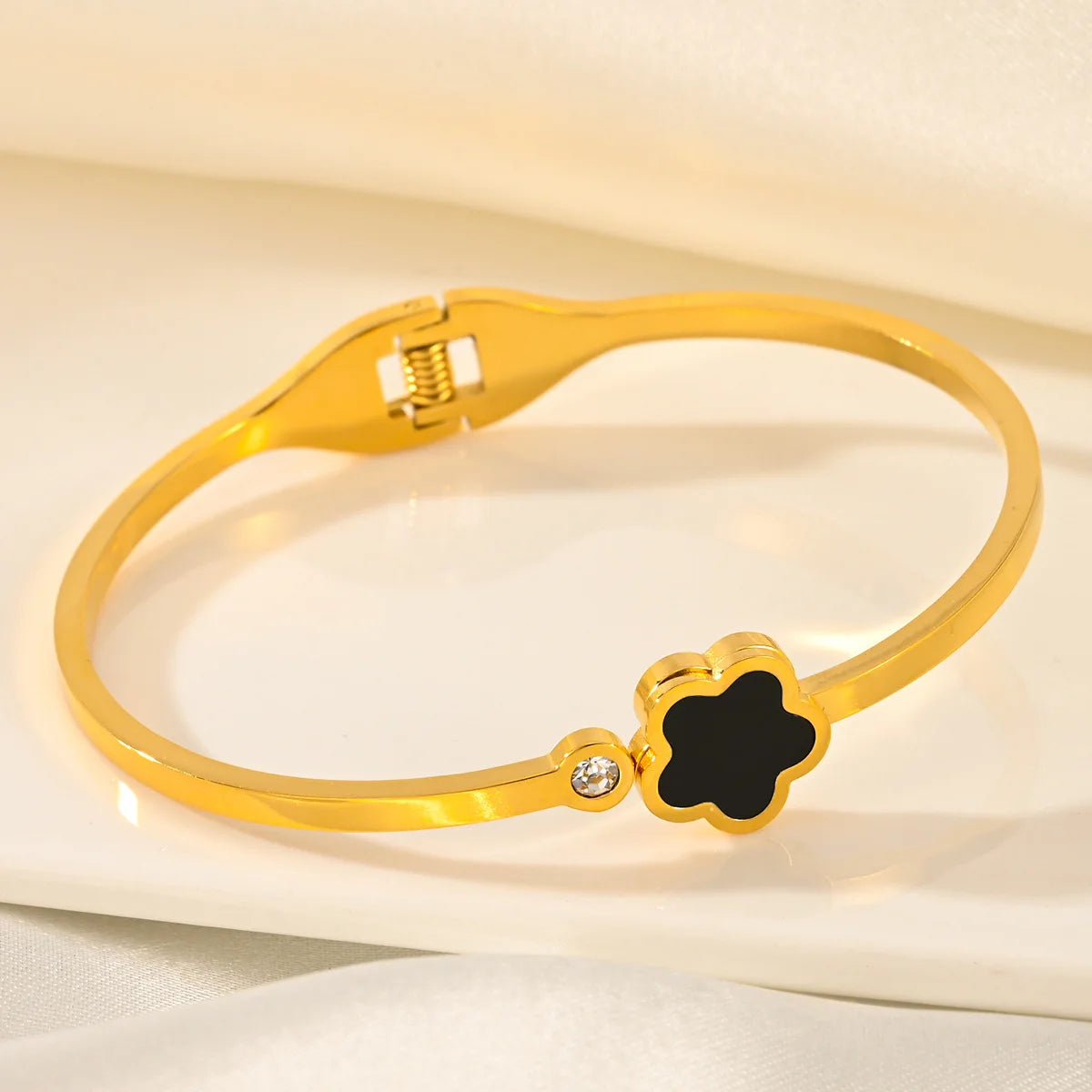Gold bracelet with a black clover-shaped clasp