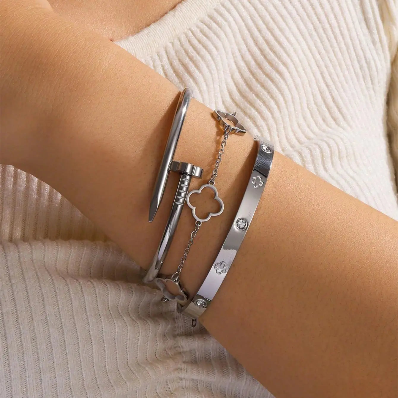 Silver bracelets on a wrist with a neutral background