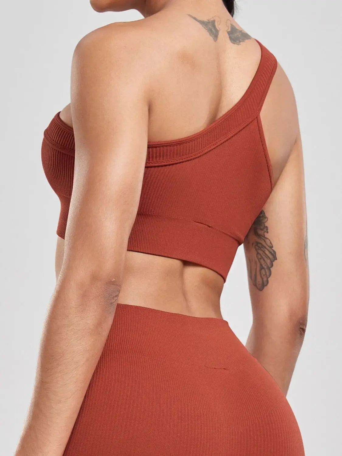 Person wearing a rust-colored one-shoulder top and pants