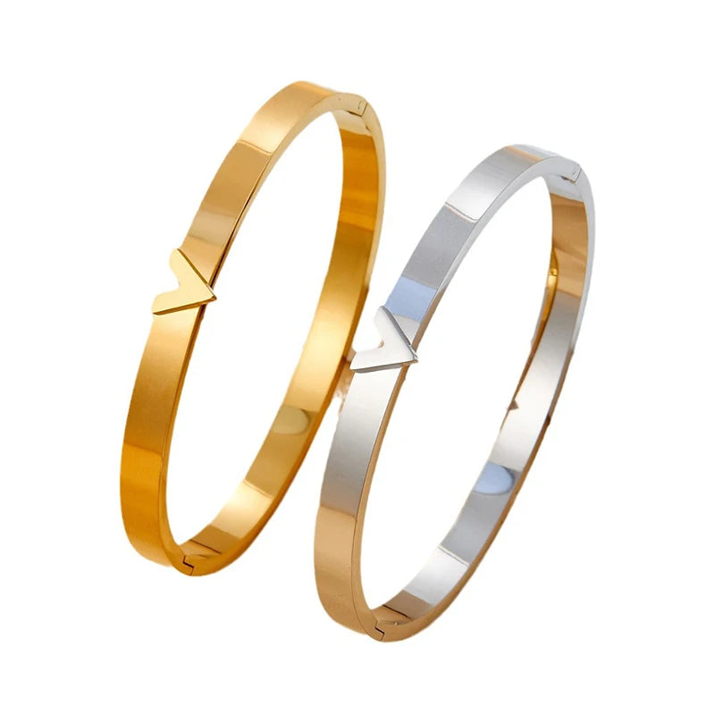 Two gold bangles, one gold and one silver, v bracelets