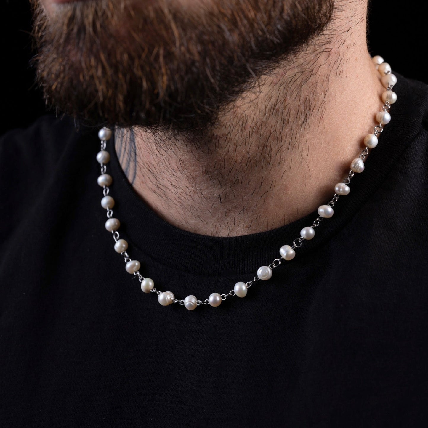 Pearl necklace worn by a person on a black background