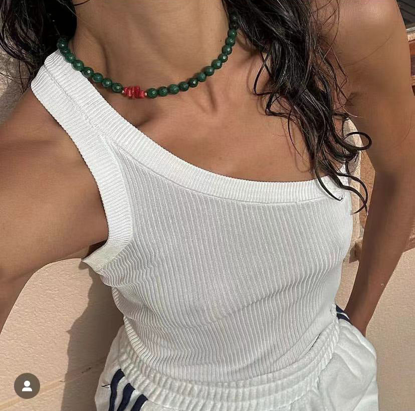 Person wearing a white sleeveless top with a green beaded necklace.