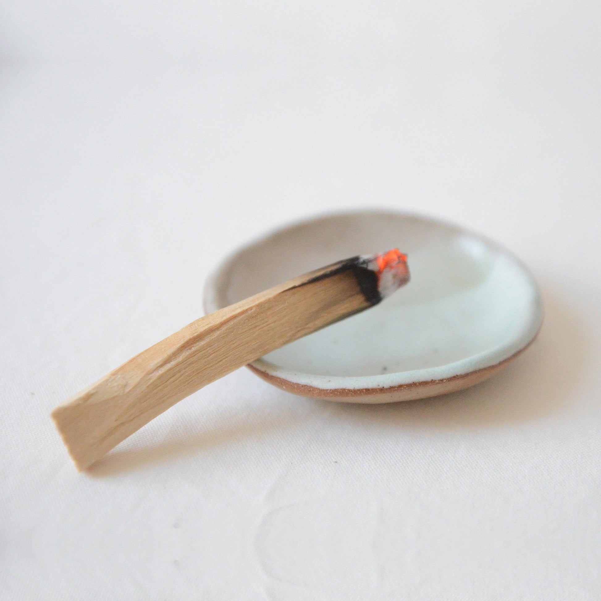 palo santo wood with lit end on a small ceramic dish