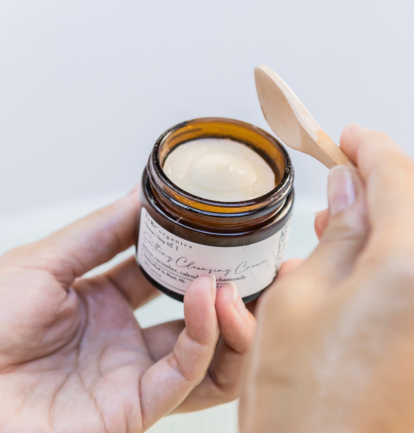 Person holding a jar of the best cream with a wooden applicator