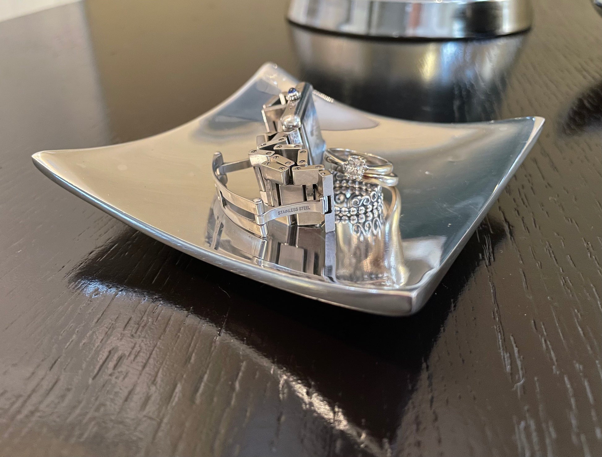 Silver jewelry display with rings on a reflective surface