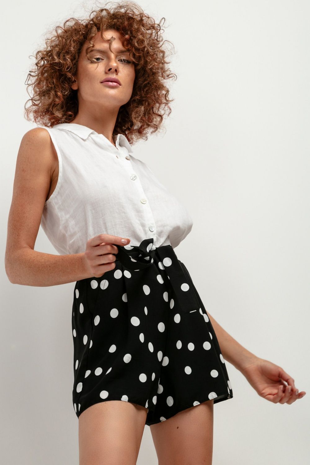 white sleeveless top and black polka dot shorts