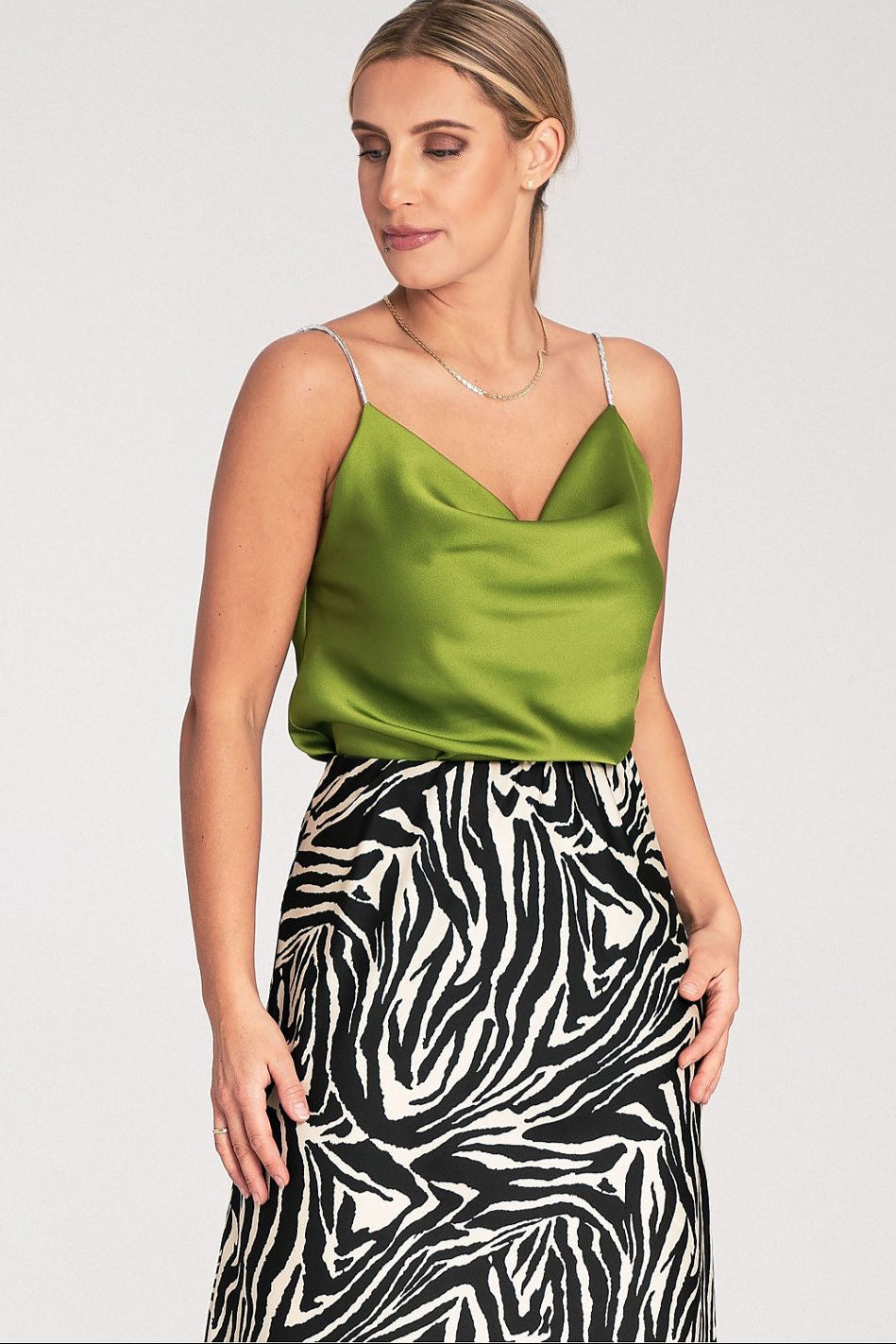 model wearing a green satin top and zebra print skirt