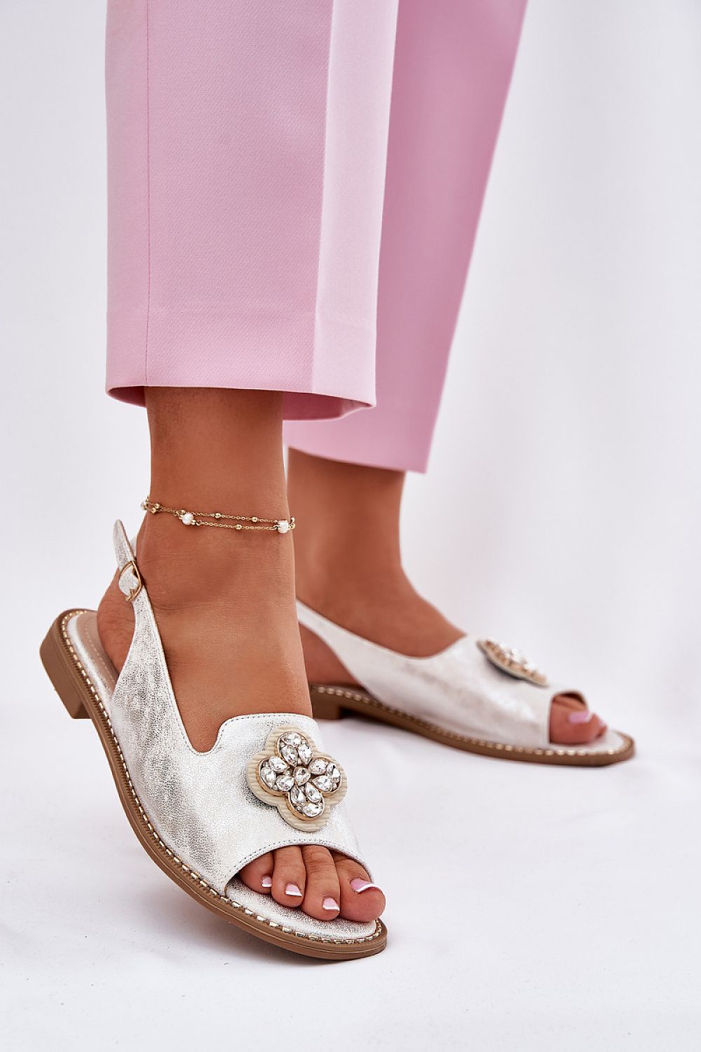 White leather sandals with a decorative brooch