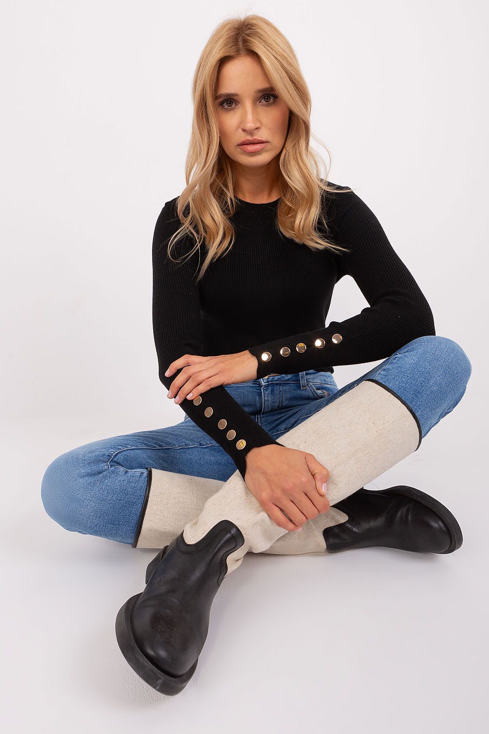 a black long-sleeve top with button details, blue jeans, and black boots.