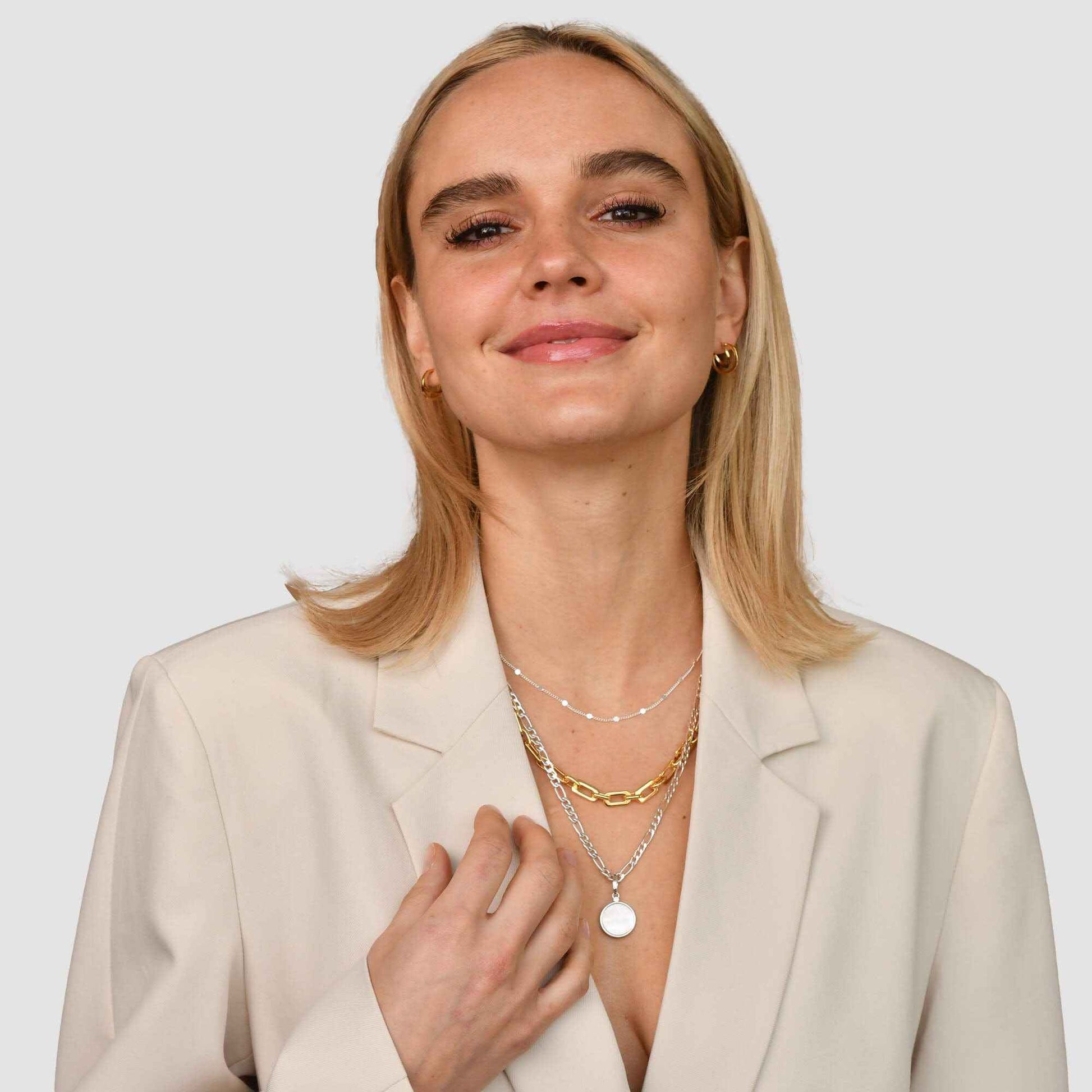 Woman wearing layered silver and gold necklaces