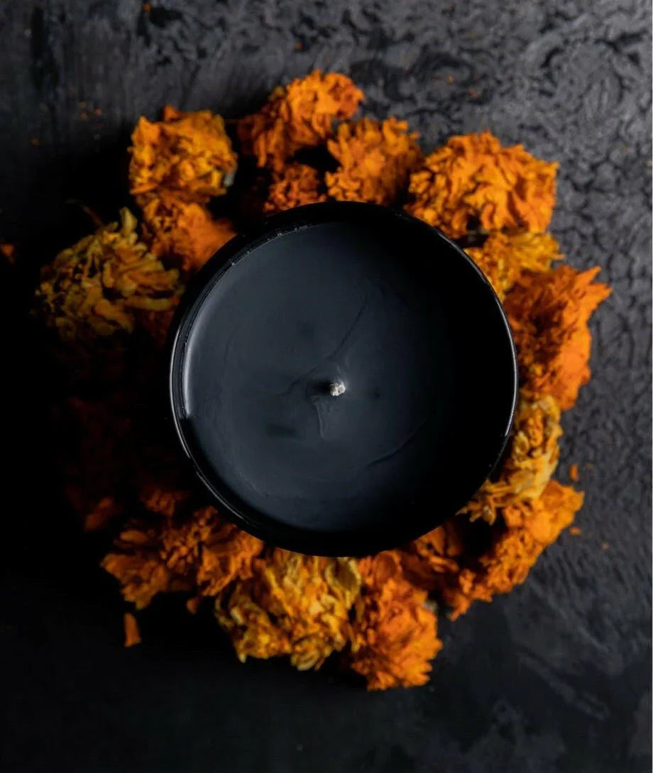Black candle in a decorative wreath made of orange and yellow flowers