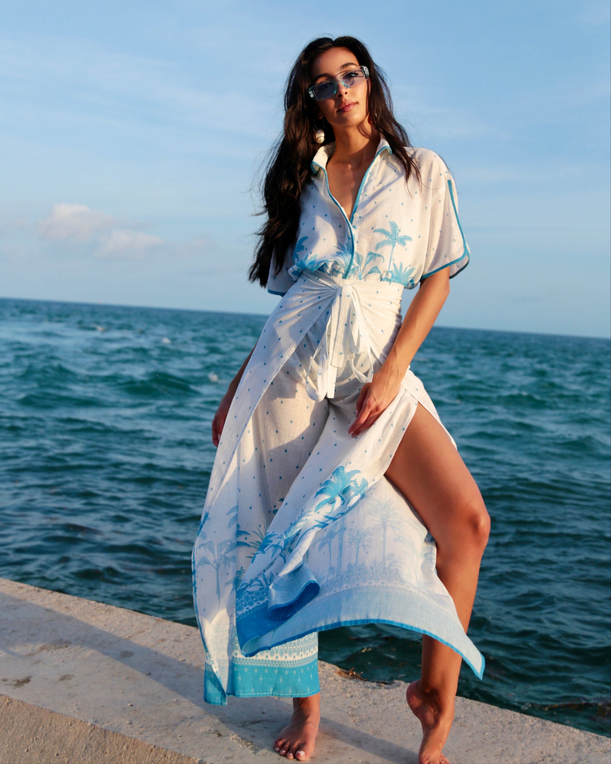 Woman in a white and blue dress standing by the ocean
