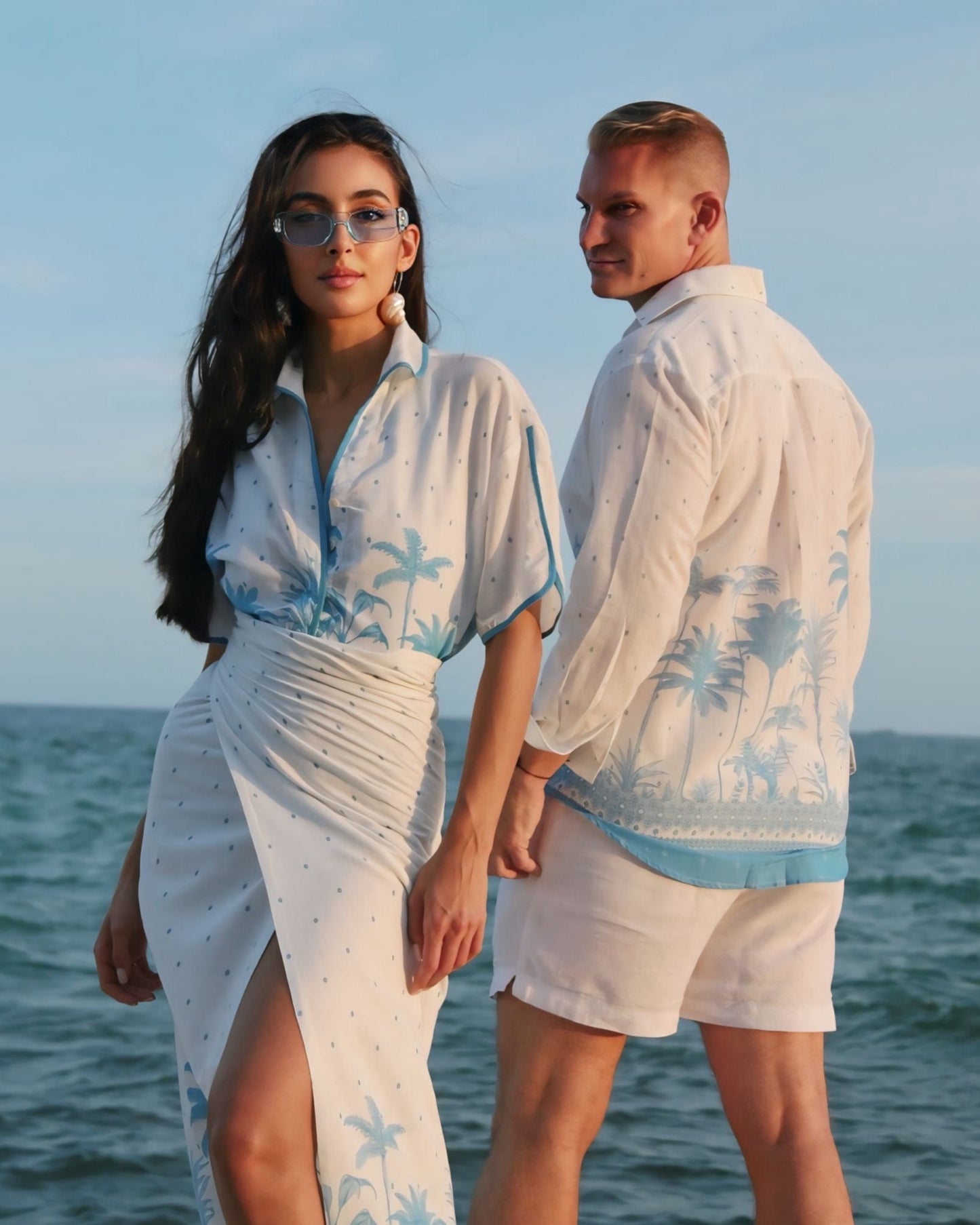 Two people in matching outfits standing by the ocean.