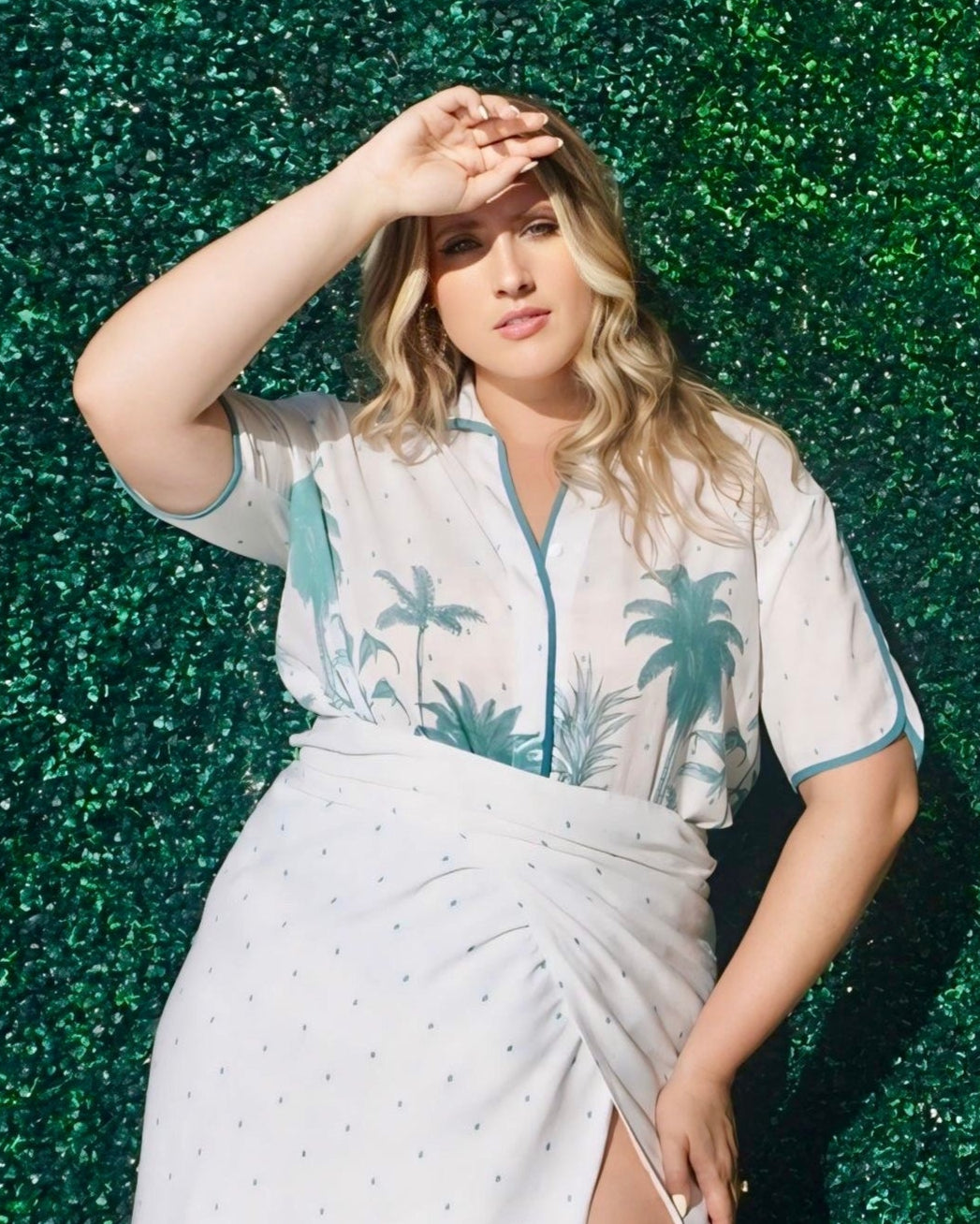Woman wearing a white dress with palm tree patterns against a green textured background