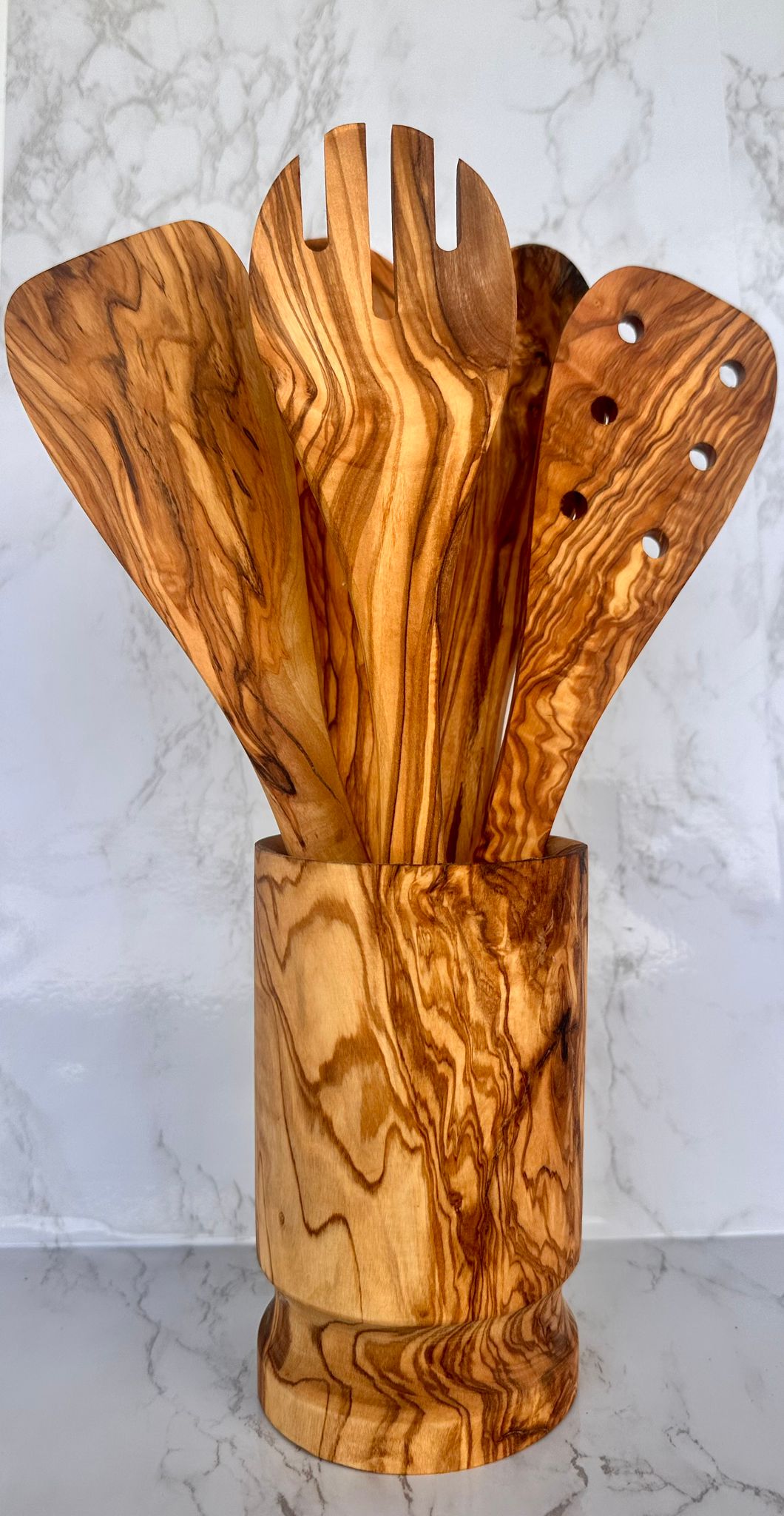 Set of wooden kitchen utensils in a holder on a marble surface