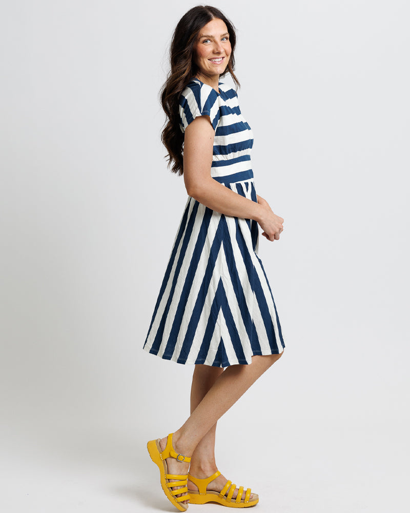 Woman wearing a blue and white striped dress with yellow sandals 