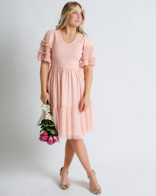 Woman wearing a pink dress holding flowers